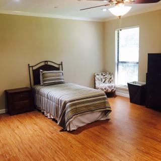 A tidy bedroom with a single bed and wood flooring.