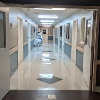 A brightly lit hospital corridor with multiple doors on either side.