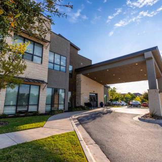 Modern building entrance with a covered driveway and clear blue sky.