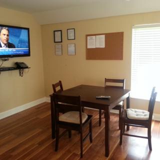 A small office conference room with a table, chairs, and a wall-mounted television.