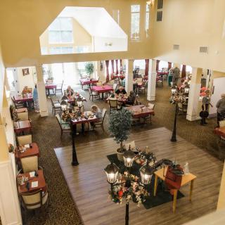 A spacious dining area with elegantly arranged tables and chairs, featuring warm lighting and tasteful decor.