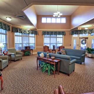 A cozy lobby area with sofas and armchairs arranged around a central table, surrounded by large windows.