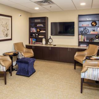 A cozy waiting room featuring comfortable chairs, bookshelves, and a television.