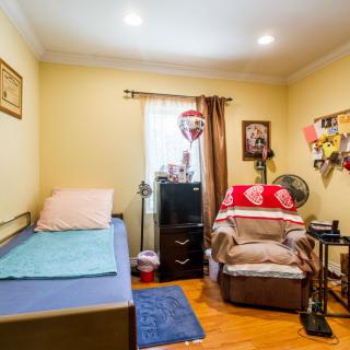 A cozy bedroom with a single bed, armchair, and television.