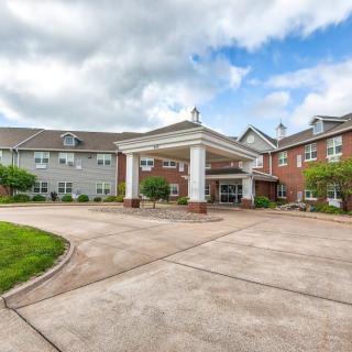 A well-maintained building with a grand entrance and circular driveway under a cloudy sky.