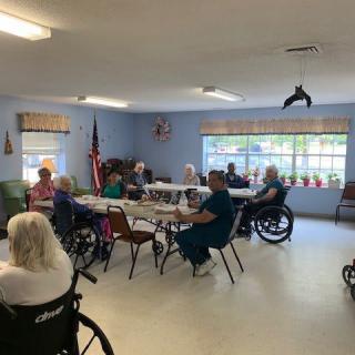 A group of elderly individuals in wheelchairs gather in a common room at a nursing home.