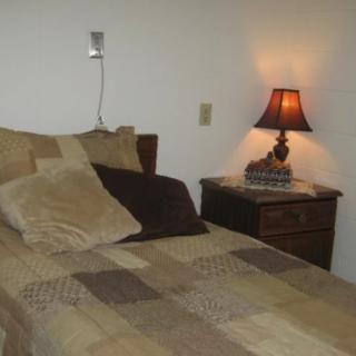 A cozy bedroom setup featuring a bed with multiple pillows and a nightstand with a lamp.