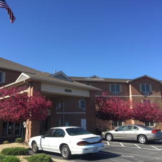 A brick building with a parking lot and two cars under a clear blue sky.
