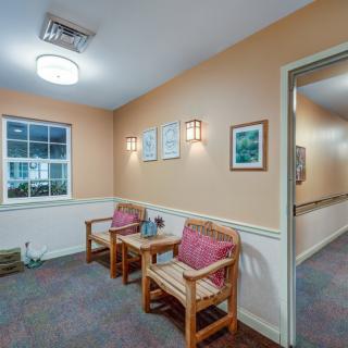A cozy waiting room with two wooden chairs and paintings on the wall.