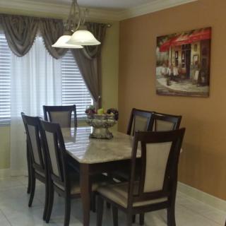 A cozy dining room featuring a wooden table with matching chairs, elegant curtains, and tasteful wall art.