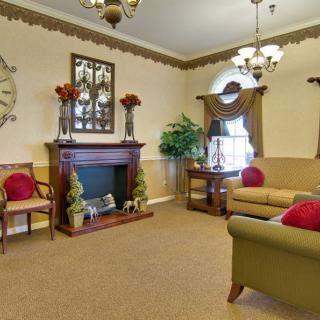 A traditional living room featuring a fireplace, sofas, armchairs, and decorative plants.