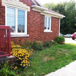 A brick house with a small garden featuring yellow flowers near the driveway.