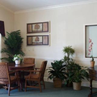 A cozy living room with a table and chairs surrounded by plants and wall art.
