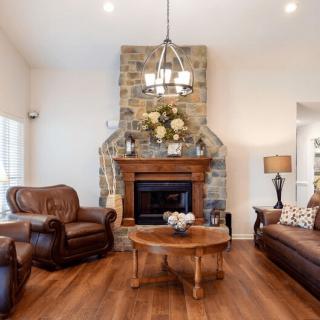 A cozy living room with leather furniture and a stone fireplace.
