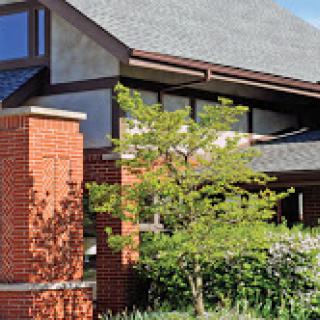 A modern brick building with large windows and lush landscaping.