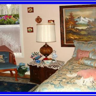 A cozy vintage-style bedroom with a lamp, decorative pieces, and a landscape painting.