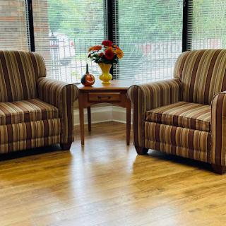 A cozy seating area featuring two striped chairs and a decorative table with flowers.