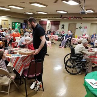 A lively community gathering at a senior center, where residents enjoy meals and engage in social activities.