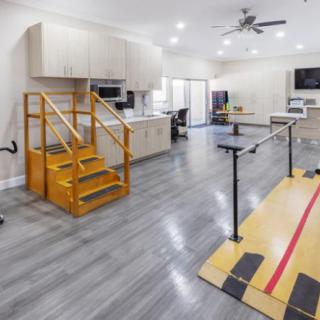 A modern rehabilitation room equipped with physical therapy tools, including parallel bars and stairs with a railing.