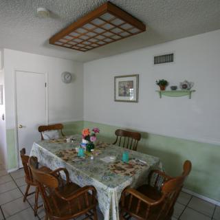 A cozy dining room with a table set for a meal, surrounded by wooden chairs and decorated with floral arrangements.