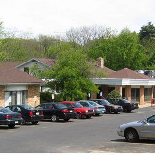 A suburban parking lot with several cars parked in front of a building.