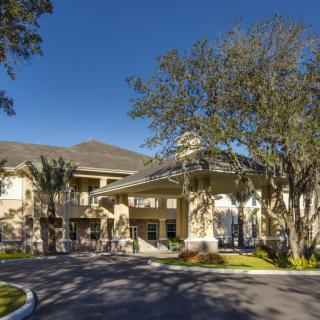 A large building with a grand entrance surrounded by trees and landscaping on a sunny day.