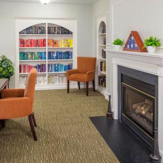 A cozy reading room with colorful bookshelves, comfortable chairs, and a fireplace.