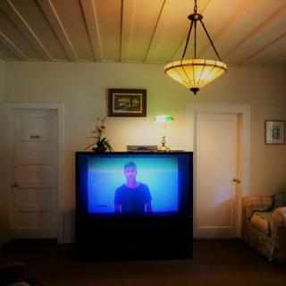 A cozy living room with a vintage television displaying a show, surrounded by classic decor and lighting.