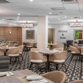 A modern restaurant dining area with neatly arranged tables and chairs, featuring stylish lighting and decor.