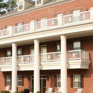 A brick building with white columns and multiple balconies.