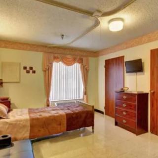 A cozy bedroom featuring a single bed, dresser, and wall-mounted TV.