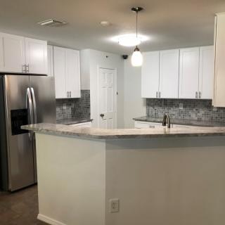 A modern kitchen with white cabinets, stainless steel appliances, and a stylish backsplash.