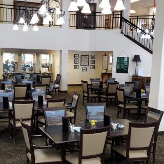 A neatly arranged dining area with tables and chairs, illuminated by hanging lights.