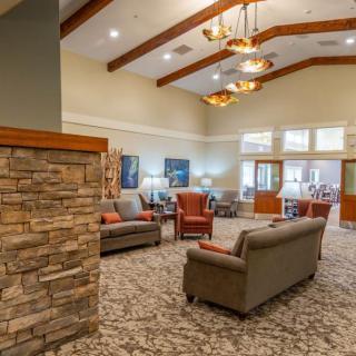 A spacious lobby with comfortable seating, featuring stone accents and wooden beams.