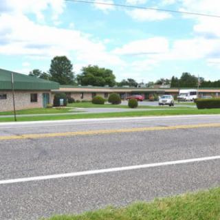 A roadside motel with a parking area and surrounding greenery.