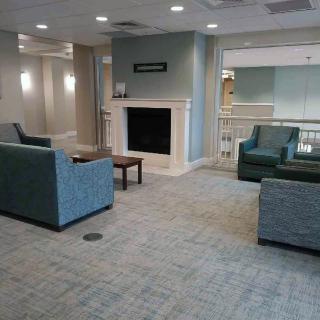 A modern living room with blue sofas, a fireplace, and carpeted flooring creating a cozy atmosphere.