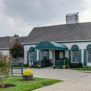 A quaint restaurant with a green awning and landscaped surroundings.