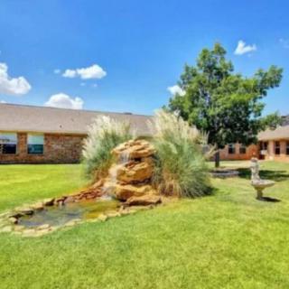 A peaceful garden with a decorative rock and pond in front of a building.