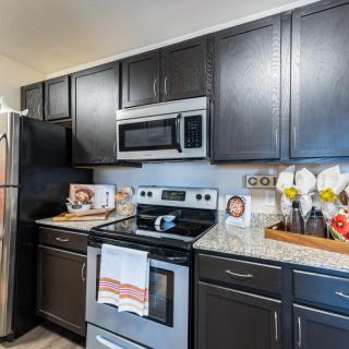 A modern kitchen with dark cabinets and stainless steel appliances.