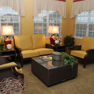 A cozy living room with yellow sofas, armchairs, a coffee table, and warm lighting from lamps.