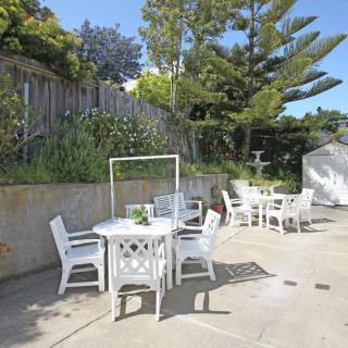 An outdoor patio area with white tables and chairs on a sunny day.