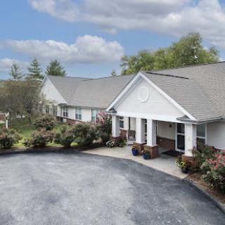 A view of a well-maintained residential building with landscaped gardens and a driveway.
