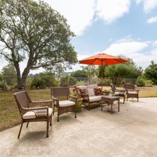 A comfortable outdoor patio setup with chairs, a table, and an umbrella in a garden setting.