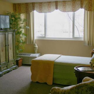 A cozy bedroom featuring a bed, a television, and natural light from the large window.
