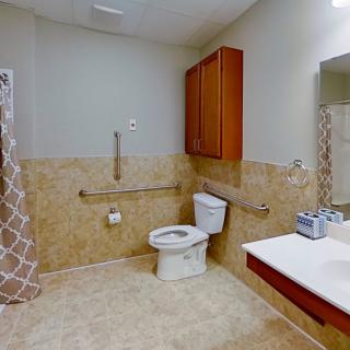 An accessible bathroom with a toilet, sink, and safety grab bars.