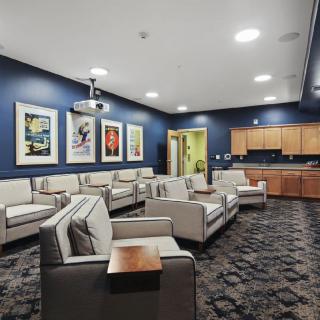 A modern conference room with comfortable seating, a projector, and art-decorated walls.