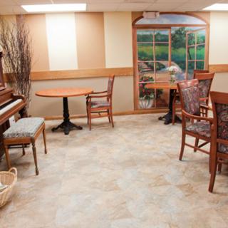 A cozy room with a piano and seating area, featuring a decorative window mural.