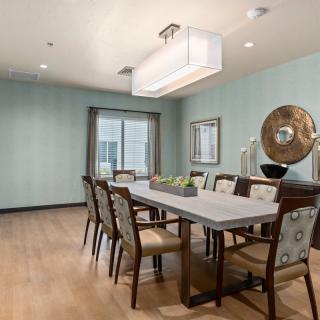 A modern dining room featuring a long table and elegant chairs under a rectangular chandelier.