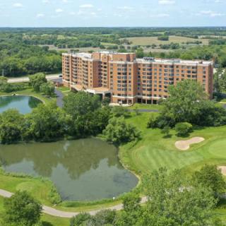 Aerial view of a residential building surrounded by a golf course and ponds.