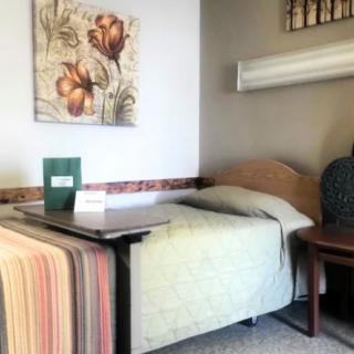 A small, cozy bedroom with a single bed, a bedside table, and wall art.